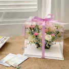 Flower gift box with pink and white flowers, wrapped in clear plastic and tied with a pink ribbon.