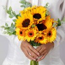 Bridal bouquet of sunflowers and gerbera daisies with greenery.