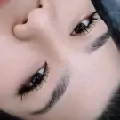Close-up of a person's eyes with long, dark eyelashes and well-groomed eyebrows.