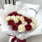Red scarlet bouquet with white carnations and red roses, wrapped in white paper.