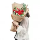 A bouquet of red roses and baby's breath wrapped in kraft paper with "Gorgeous You" printed on it.