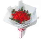 A bouquet of red roses wrapped in white paper with a red ribbon.