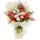 Pink roses and red orchids in a bouquet with a green ribbon.