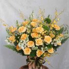 A wooden box arrangement of yellow roses, accented with delicate yellow and white flowers.
