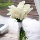 Bouquet of white calla lilies tied with white lace ribbon.