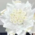 A bouquet of white roses wrapped in white paper with yellow ribbon accents.