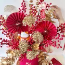 Maneki-neko cat with red and gold floral arrangement, featuring red paper fans.