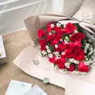 Bouquet of red roses and white daisies in elegant wrapping.