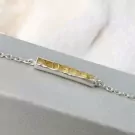 Silver bracelet with a raw yellow crystal bar pendant.