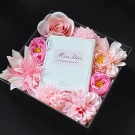 Dior Miss Blooming Bouquet EDT perfume box surrounded by pink artificial flowers.