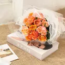 Orange and pink roses in a bouquet on a Vogue book.