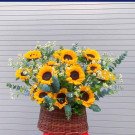 A basket of sunflowers and small white flowers.