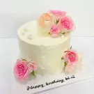 Cream cake adorned with pink and peach roses, pearl sprinkles, and "Happy birthday" text.