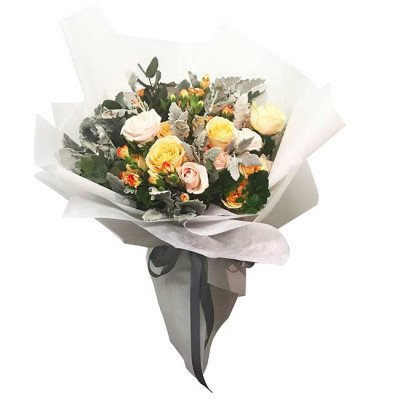 A bouquet of yellow and pink roses with greenery, wrapped in white and gray paper.