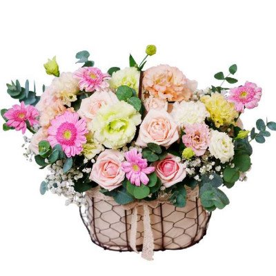 Pastel pink and cream flower arrangement in a wire basket with lace ribbon.