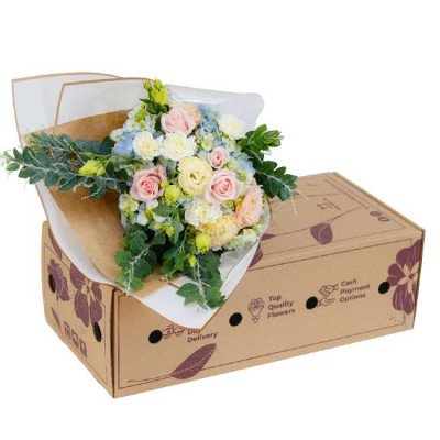 A bouquet of pastel roses, carnations, lisianthus, and hydrangeas in a gift box.