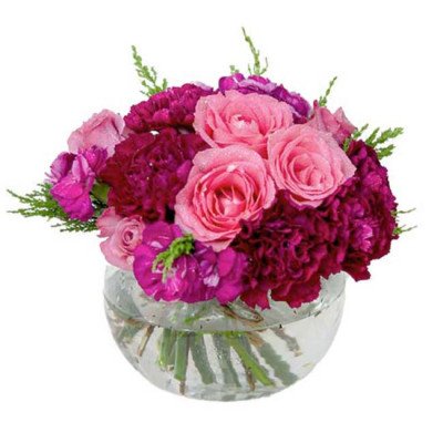 Round glass vase of pink roses and deep purple carnations with greenery.