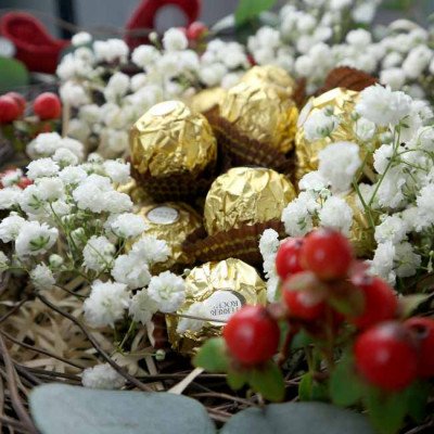 Ferrero Rocher chocolates nestled with white baby's breath flowers and red berries.