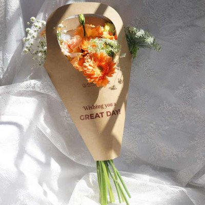 Orange gerbera daisy and carnation bouquet in brown paper wrapping with "Wishing you a GREAT DAY!"
