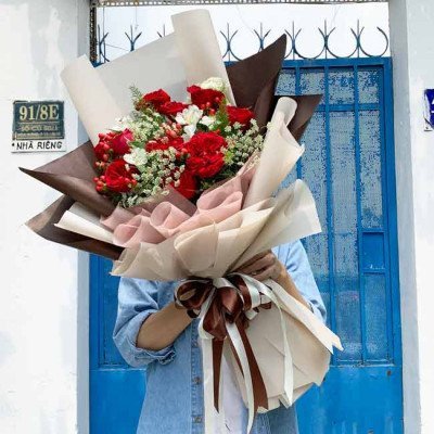 Red and white rose bouquet with baby's breath, wrapped in brown and cream paper, tied with a brown ribbon.