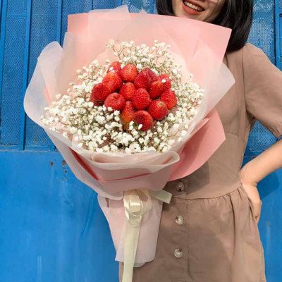 Strawberry and baby's breath bouquet in pink and white wrapping with a ribbon.