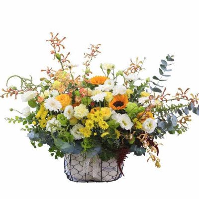 Basket of yellow and white flowers with sunflowers and orchids, eucalyptus, and greenery.
