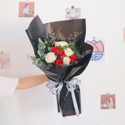 Bouquet of red and white roses with silver ribbon on black wrapping paper.