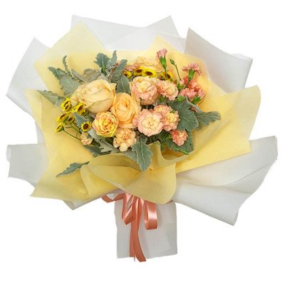 A bouquet of yellow roses, pink carnations, and yellow daisies wrapped in yellow and white paper with a peach ribbon.