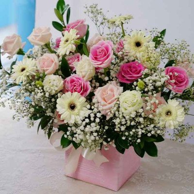 Pink box of roses, gerberas, and baby's breath flowers, with a ribbon bow.