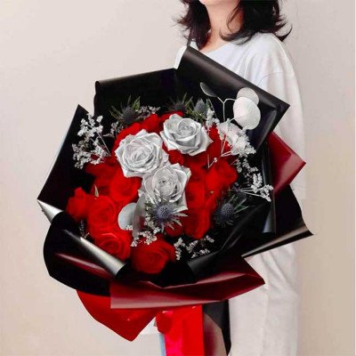 Red and silver roses in a bouquet with black and red wrapping.
