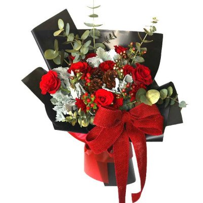 Red roses, carnations, pinecones, and eucalyptus in a black bouquet with a red burlap bow.