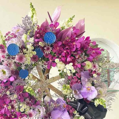 Purple and pink floral arrangement with orchids and anthuriums, featuring blue decorative accents.