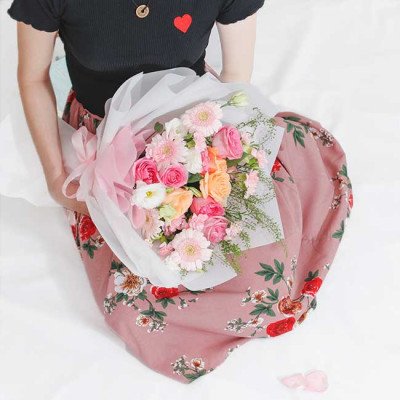 A person holding a bouquet of pink and orange flowers.