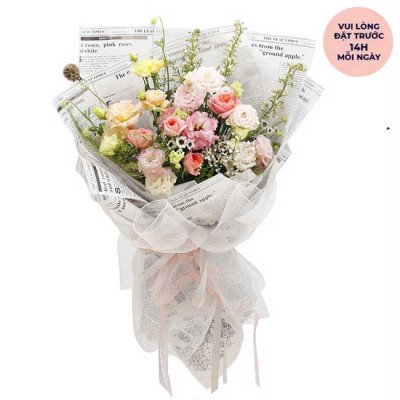 Bouquet of pink and yellow roses and lisianthus wrapped in newspaper and white mesh.