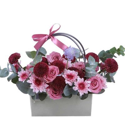 Basket of pink roses, burgundy and pink chrysanthemums, and eucalyptus with a pink ribbon.