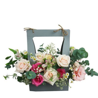 Pastel roses, alstroemeria, and other flowers in a grey floral box with a handle.