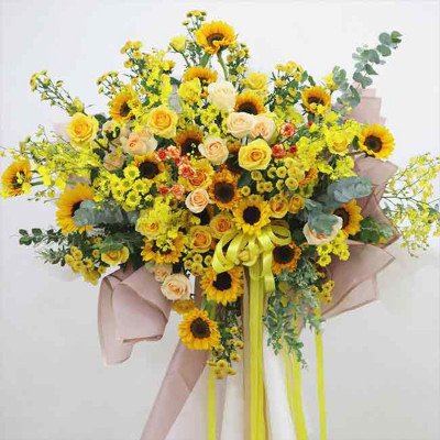 Yellow flower arrangement with sunflowers, roses, orchids, and mums.