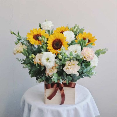 Wooden box with sunflowers, lisianthus, and other greenery, tied with a brown ribbon.
