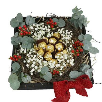 Ferrero Rocher chocolates nestled in baby's breath, eucalyptus, and red berries in a rustic box with a red bow.