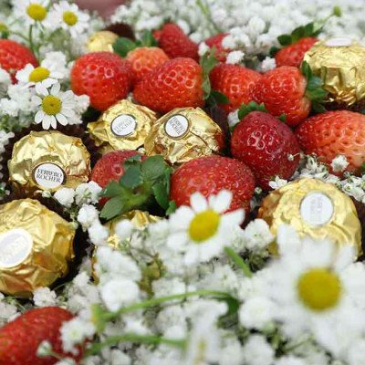 Strawberries and Ferrero Rocher chocolates surrounded by white flowers.