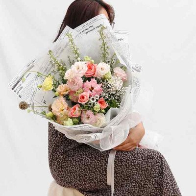A bouquet of pink and white roses and other flowers wrapped in newspaper.