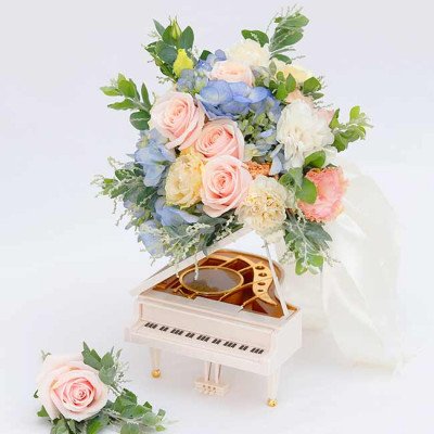 Pastel wedding bouquet with roses, carnations, eustoma, and hydrangeas on a miniature piano.