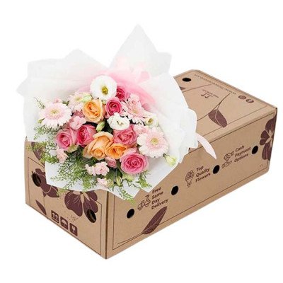 A bouquet of pink and orange roses, gerberas, and eustoma in a gift box.
