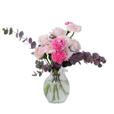 Pink roses, carnations, and gerbera daisies in a glass vase with eucalyptus leaves.