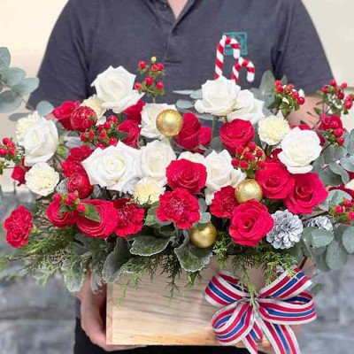 Christmas flower box with red and white roses, carnations, pine cones, and gold ornaments.