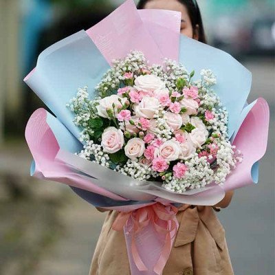 Bouquet of pink roses and carnations with baby's breath, wrapped in blue and pink paper.
