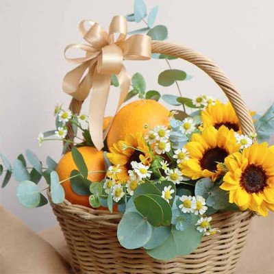 Basket of sunflowers, oranges, and eucalyptus with a golden bow.