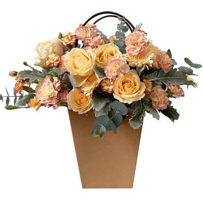 Floral arrangement in a brown paper bag with yellow roses, pink carnations, and eucalyptus.