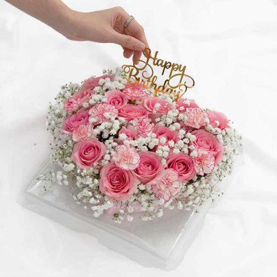 Pink rose and carnation floral cake with baby's breath and "Happy Birthday" topper.
