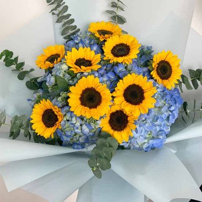 Bouquet of sunflowers and blue hydrangeas with eucalyptus leaves.